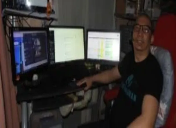Eduardo Jalandoni sitting infron of his computer with 3 monitors