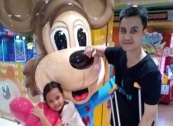 Joe Angelo Cuevas poses beside a life-size mickey mouse together with his daughter